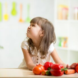 child girl with expression of disgust against vegetables