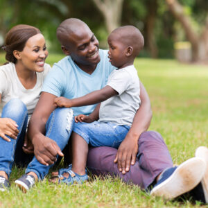 young african family of three sitting together outdoors
